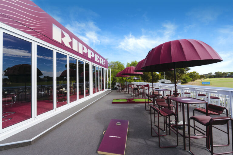 a modular temporary building with Glass bifold doors looking onto a raised deck with tables and umbrellas