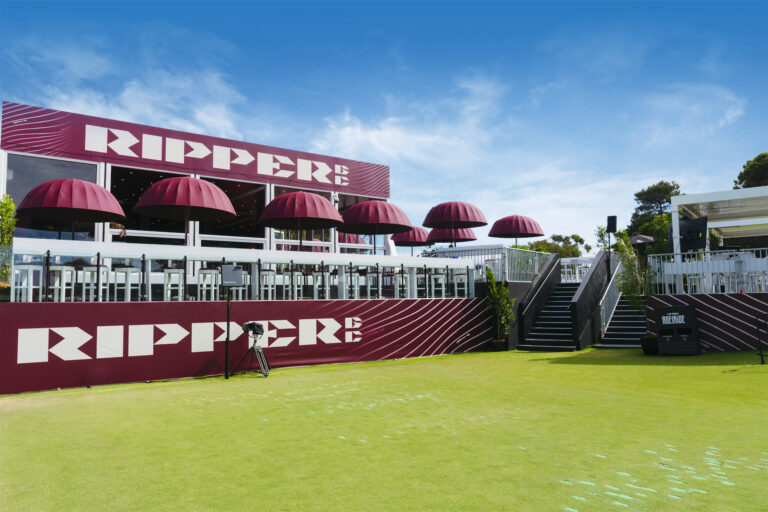 a building with purple umbrellas and a green lawn